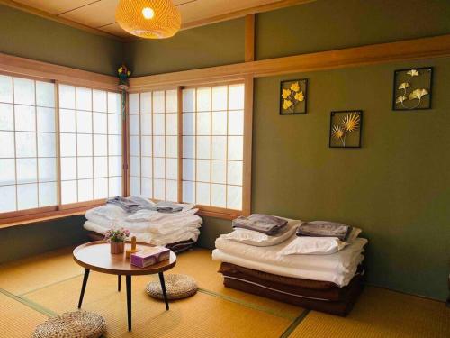 a room with three mattresses and a table and windows at 熱海星海台 星の輝きを導く石の小道 海景BBQの空間 大島を望む 日の出と夜景 in Atami