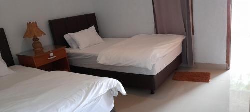 a bedroom with two beds and a night stand with a bed sidx sidx sidx sidx at Swan Homestay in Labuhanpandan