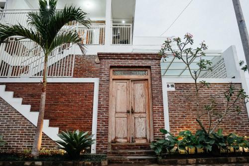 Casa de ladrillo con puerta de madera y escaleras en Emka Villa Traditional Minimalist, en Malang