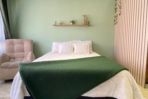 een slaapkamer met een groene deken op een bed en een stoel bij LOFT encantador, muy cómodo, al lado del MovistarA in Bogota