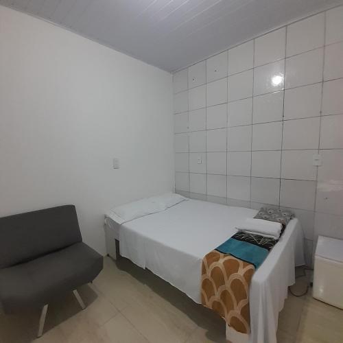 a small bedroom with a bed and a chair at Pousada Estelita in Itaparica Town