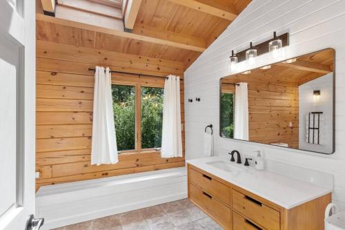 a bathroom with a tub and a sink and a mirror at Our Pondside Cabin in Westminster