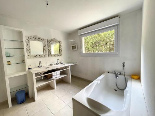 ein weißes Badezimmer mit einer Badewanne und einem Waschbecken in der Unterkunft Appartement Saint-Pair-sur-Mer, 3 pièces, 4 personnes - FR-1-361-455 in Saint-Pair-sur-Mer