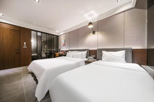 2 łóżka w pokoju hotelowym z białą pościelą w obiekcie Brown Dot Hotel Busan Station w Pusanie