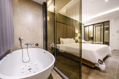 a bathroom with a bed and a bath tub next to a bedroom at Brown Dot Hotel Busan Station in Busan