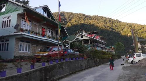 a woman walking down a street in front of houses at Coral Homestay in Pelling