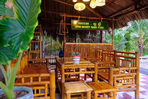 a restaurant with wooden chairs and tables and a sign at Farmstay Sokfarm in Trà Vinh