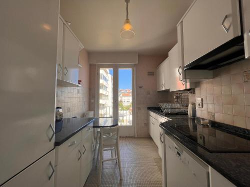 une cuisine avec des placards blancs et un tabouret. dans l'établissement Appartement lumineux, proche plage, balcon, parking, WiFi - FR-1-239-962, à Saint-Jean-de-Luz