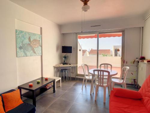 un salon avec une table et des chaises et une cuisine dans l'établissement Studio Cabine ensoleillé, terrasse, proche plage, port et commerces à Carnon-Plage - FR-1-715-72, à Mauguio