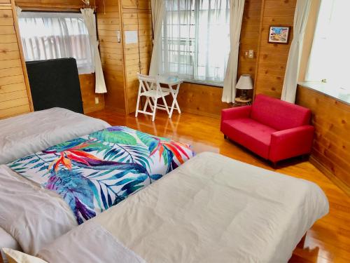 um quarto com 2 camas e uma cadeira vermelha em ゲストハウス奄美ルリカケス em Amami