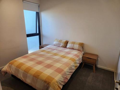 a bedroom with a bed with a plaid comforter at Modern Apartment Airport Area in Melbourne