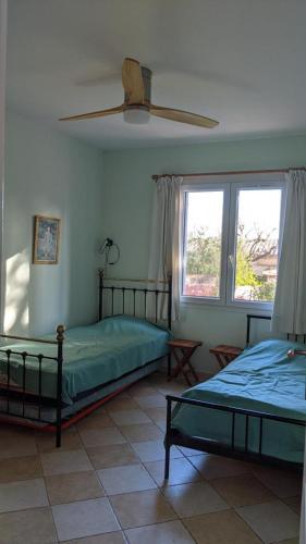 une chambre avec deux lits et un ventilateur de plafond dans l'établissement La voliere, à Toulon