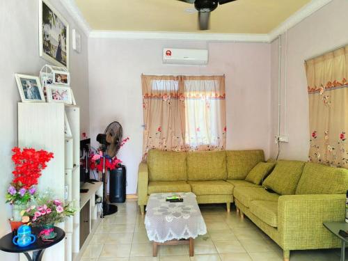 a living room with a green couch and a table at SJ Homestay & Room Rental. in Kota Belud