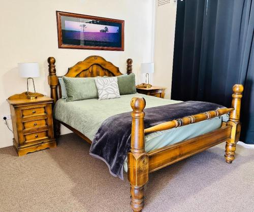 a bedroom with a wooden bed and two night stands at Flinders Ranges Motel - The Mill in Quorn