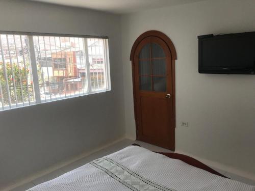 Schlafzimmer mit einem Bett, einem TV und einem Fenster in der Unterkunft Apartamento Dúplex - Barrio Maldonado Tunja in Tunja
