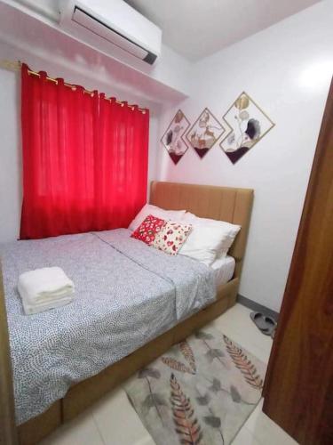 een slaapkamer met een bed met een rood gordijn bij Staycation Near MOA by Cozypura with Pay Parking at S Res MOA in Manilla