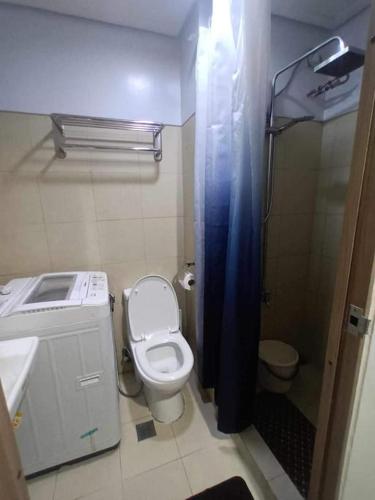 a bathroom with a toilet and a blue shower curtain at Staycation Near MOA by Cozypura with Pay Parking at S Res MOA in Manila