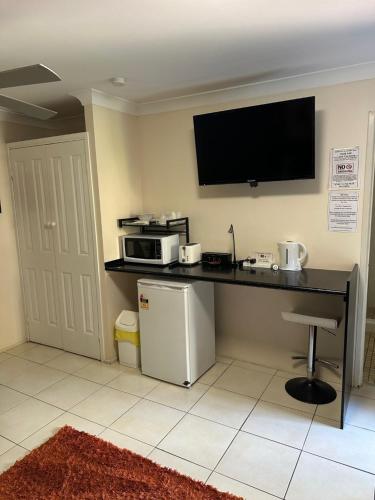 a kitchen with a counter with a microwave and a tv at Gold Coast Airport Motel - Only 300 Meters To Airport Terminal in Gold Coast