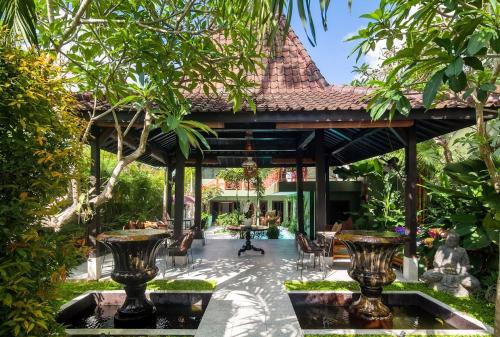 an outdoor pavilion with tables and chairs in a garden at The Lodge Canggu in Tumbak Bayuh