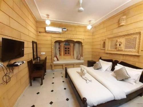 a bedroom with a bed and a desk and a television at Desert Golden Palace in Jaisalmer