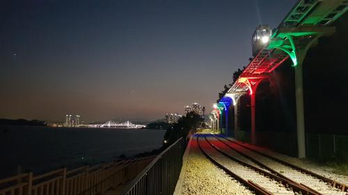 a train on a track next to the water at night at Haeundae Mipo House1 in Busan