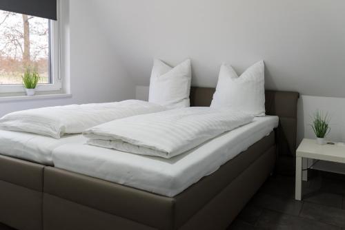ein Bett mit weißer Bettwäsche und Kissen darauf in der Unterkunft Ferienwohnung Milchverliebt in Osten