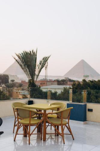 a yellow table and chairs with pyramids in the background at Regent Pyramids View in Cairo
