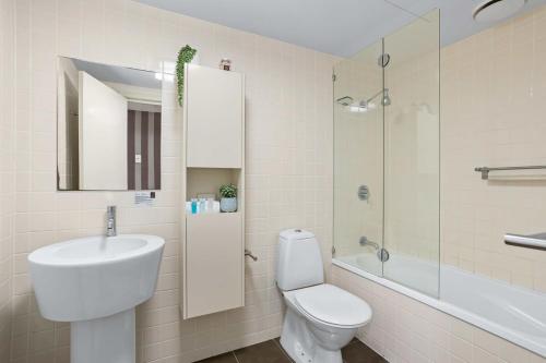 y baño con aseo, lavabo y espejo. en Cosy 1-Bed Unit with a Gym, BBQ Area, Spa and Pool en Brisbane