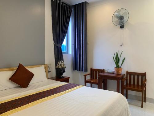 a bedroom with a bed and a desk and a window at ĐÔNG ĐÔ HOTEL Đăk Lăk in Buôn Tâng Mai