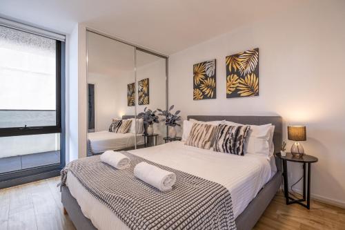 um quarto com uma cama grande e uma janela em Modern 2br Apartment With Free Carpark And Pool em Melbourne