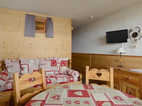 Cette chambre comprend une table, un lit et un canapé. dans l'établissement Studio rénové pied de pistes, balcon sud, 4 pers - FR-1-181-2557, à Aime La Plagne