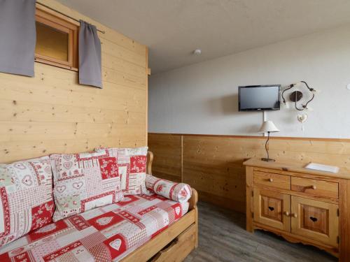 - une chambre avec un canapé et une télévision murale dans l'établissement Studio rénové pied de pistes, balcon sud, 4 pers - FR-1-181-2557, à Aime La Plagne