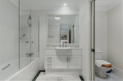 a white bathroom with a sink and a shower at Modern apartment in the heart of Canberra in Kingston 