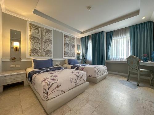 um quarto de hotel com duas camas e uma secretária e uma secretária em At Pingnakorn Hotel em Chiang Mai