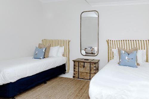 Un dormitorio con dos camas y un espejo. en The Patonga Cottage, en Patonga