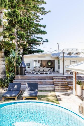 a pool with two chairs next to a house at The Patonga Cottage in Patonga Beach
