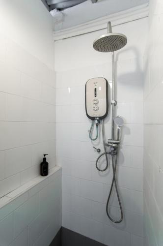 a shower in a white tiled bathroom with a shower head at Aayu Melayu - George Town Penang in George Town