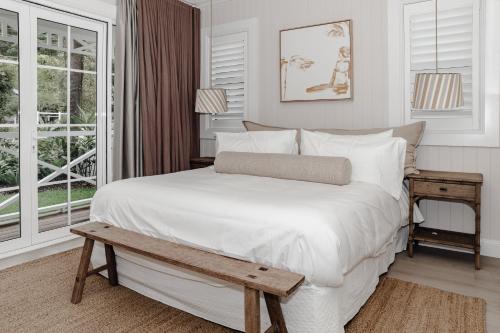 - une chambre avec un lit blanc, une table et des fenêtres dans l'établissement Bay Cottage, à Patonga Beach