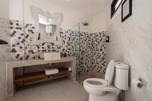 a bathroom with a toilet and a sink and a mirror at Komodo Suites Downtown in Labuan Bajo