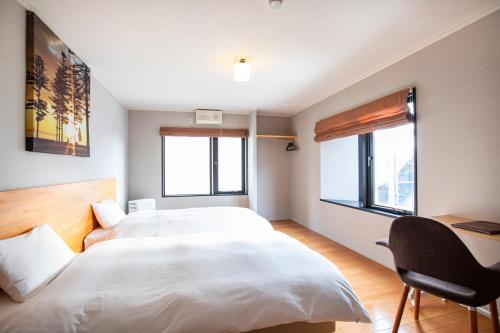 1 dormitorio con 2 camas, escritorio y 2 ventanas en M Lodge, en Niseko