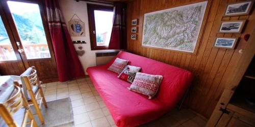 a red couch with two pillows on it in a room at Résidence Le Centre - Studio pour 4 Personnes MAE-3345 in Champagny-en-Vanoise