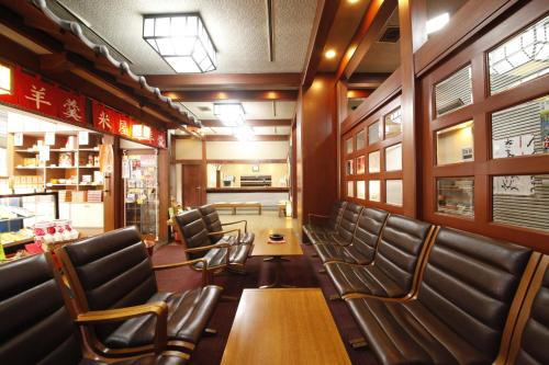 a restaurant with wooden tables and leather chairs at Wakamatsu Honten in Narita