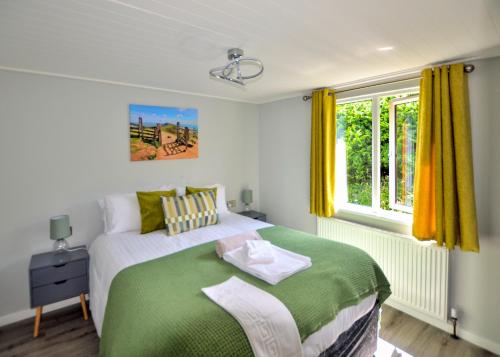 LongnorにあるLongnor Wood Holiday Parkのベッドルーム(緑と白のベッド、窓付)