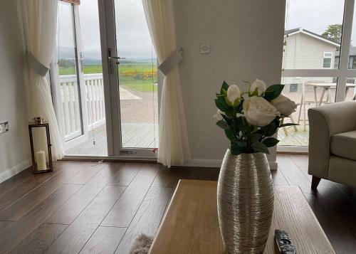 a vase with white roses in a living room at Royal Arch Park in Fettercairn