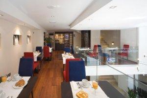 un restaurante con mesas y sillas y un comedor en Hotel Arena, en Gijón
