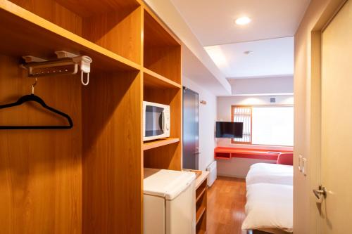 ニセコ町にあるエム ホテル 二セコのベッド1台、電子レンジが備わる小さな客室です。