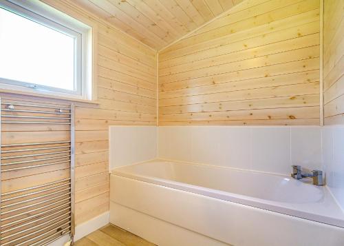 a bathroom with a tub and wooden walls at Messingham Lakes in Messingham
