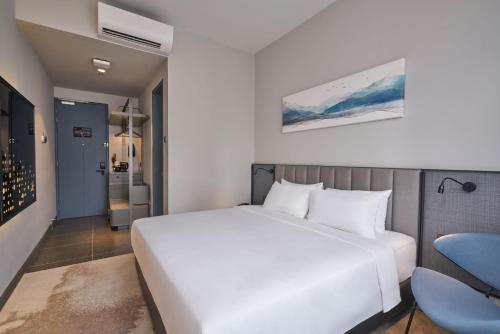 um quarto com uma cama branca e uma cadeira azul em Sleeping Lion Suites em Kuala Lumpur