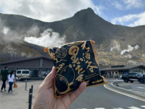 a hand holding a bag with a mountain in the background at HAKONE DOMA in Hakone