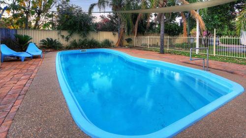 a large blue swimming pool with two blue chairs at Highway Tourist Village in Narrabri